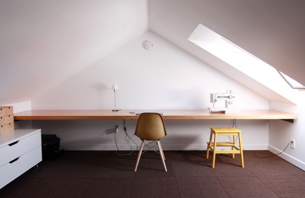 two chairs and a desk in an attic space with slanted ceiling, white walls, and brown carpet