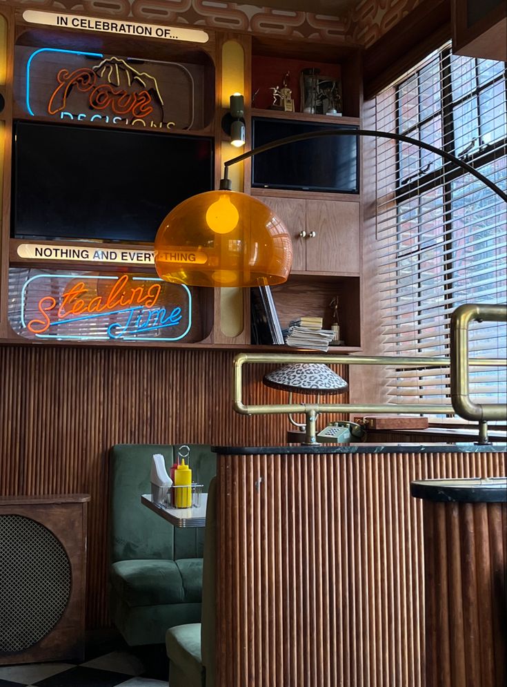 the interior of a diner with neon signs on the wall and wood paneled walls