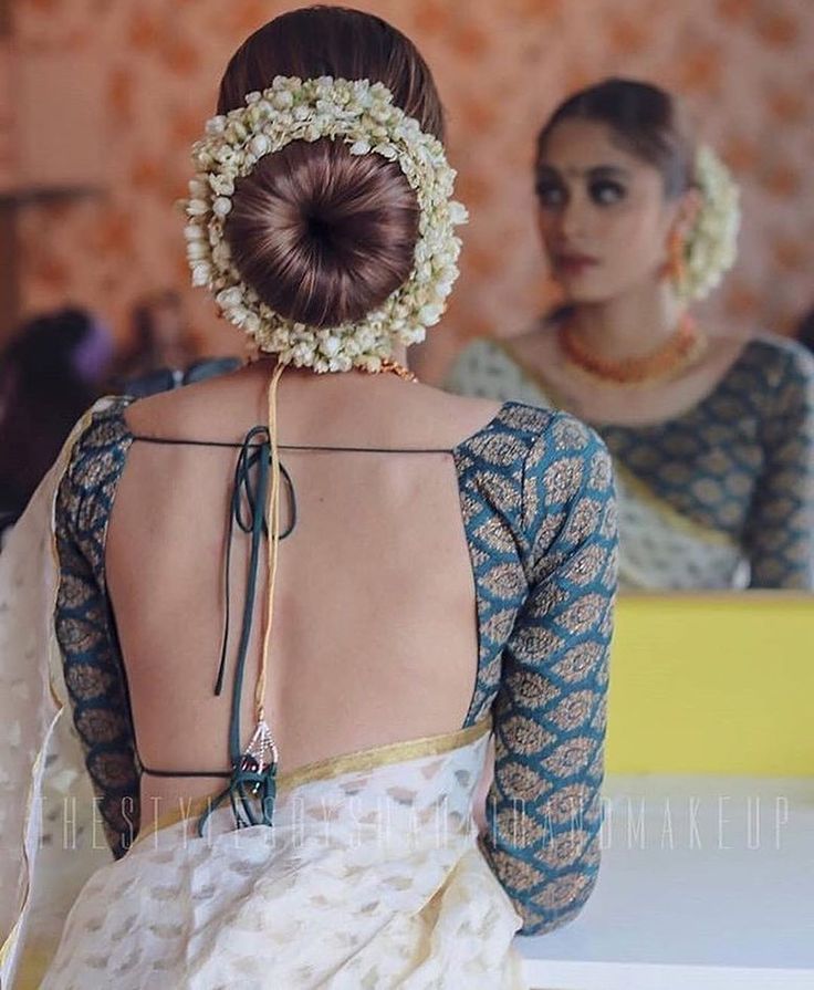 the back of a woman's head with flowers in her hair, and two other women behind her