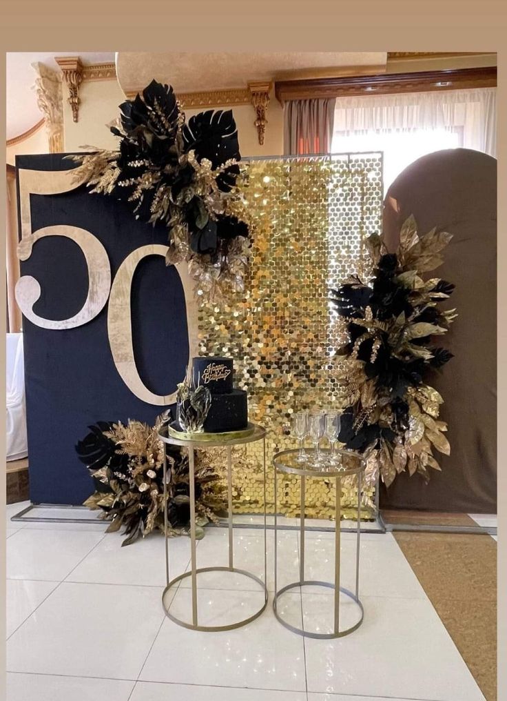 a table topped with black and gold flowers next to a sign that says 50 on it