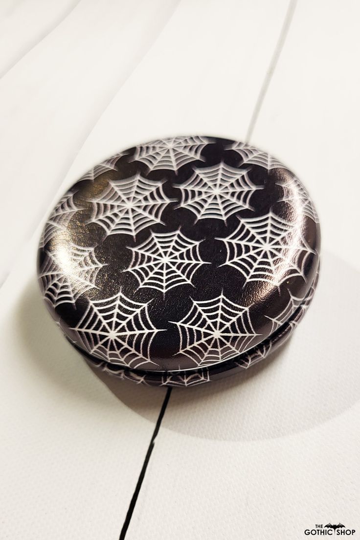 a black and white box sitting on top of a wooden table next to a spider web pattern