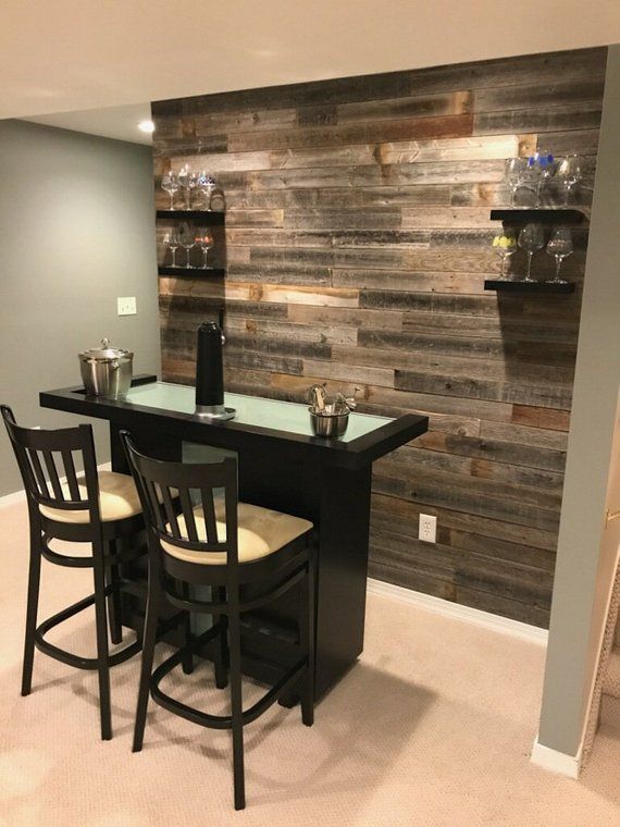 a bar with three stools in front of a wall made out of wood planks