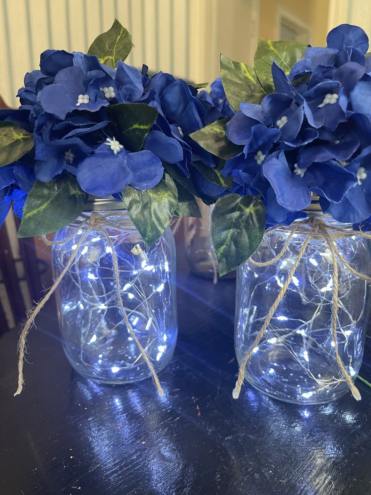 two mason jars with blue flowers in them