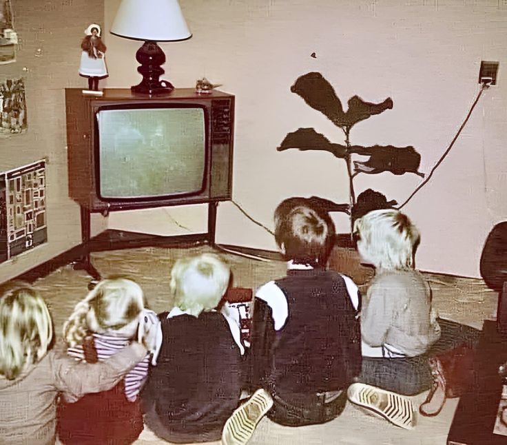 four children sitting on the floor watching tv