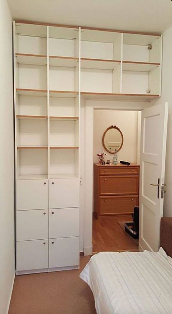 an empty bedroom with a bed, dresser and bookcases in the closet area