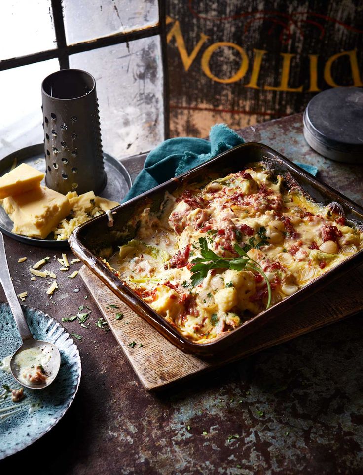 a pan filled with food sitting on top of a table next to plates and utensils