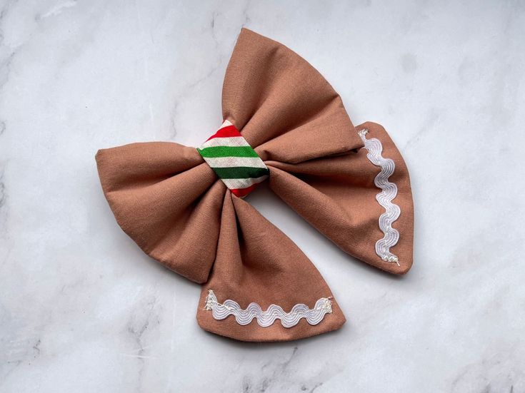 Introducing our festive Sailor Gingerbread Bow Tie. Specially designed to add a touch of holiday cheer to your furry friend Christmas outfit. Crafted with love and attention to detail, this bow tie features a delightful gingerbread cookie design, inspired by the beloved gingerbread man costume. The Sailor Gingerbread Bow Tie is not only stylish but also incredibly functional. It comes with two elastic straps at the back, allowing for easy attachment to your pet's collar. Simply slide your pet's collar through the elastic strips, and voila! Your furry companion is ready to steal the show. Whether you're gifting it to a fellow pet lover or spoiling your own adorable companion, this bow tie is sure to bring smiles and festive vibes to all. Don't miss out on the opportunity to make your pet's Dog Christmas Collar, Gingerbread Man Costume, Gingerbread Man Costumes, Candy Cane Cookie, Cookie Costume, Christmas Collar, Cats Christmas, Dog Xmas, Sailor Bow