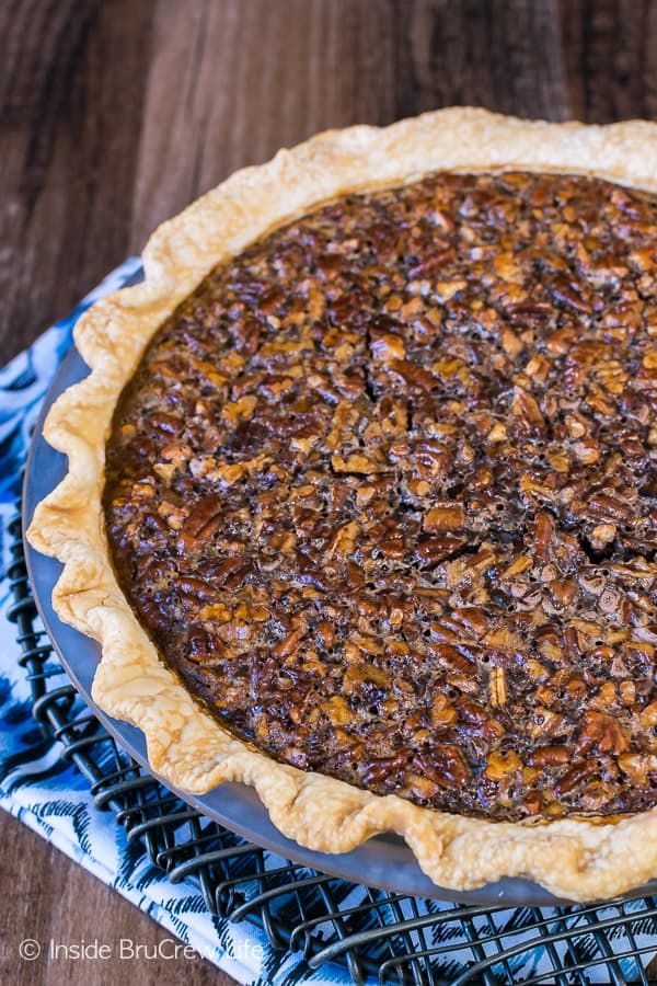 a pecan pie sitting on top of a blue and white cloth next to a wooden table