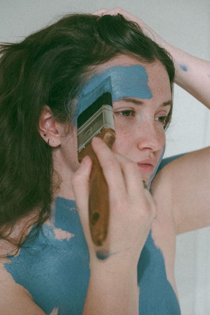 a woman with blue paint on her face brushes her hair