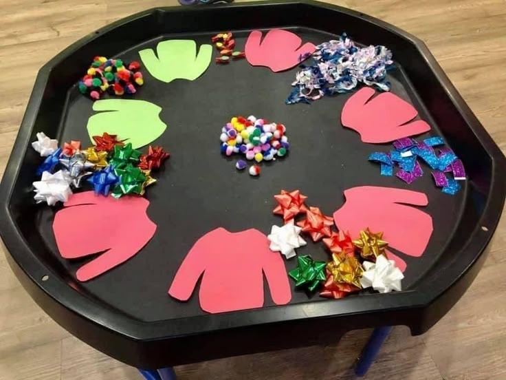 a black table topped with lots of different colored items on top of wooden flooring