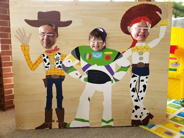 two children are standing in front of a cardboard cutout of toy story characters