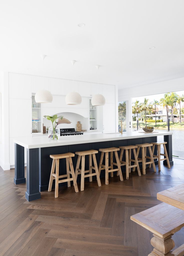 a kitchen with an island and bar stools in the center, surrounded by wood flooring