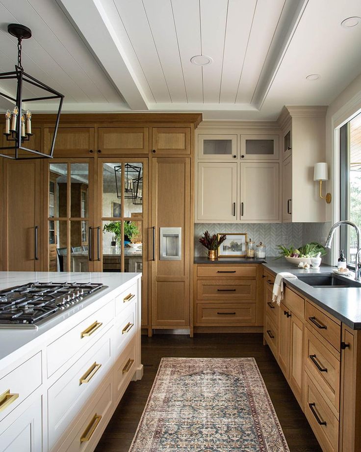 a kitchen with wooden cabinets and an area rug in front of the stove top oven