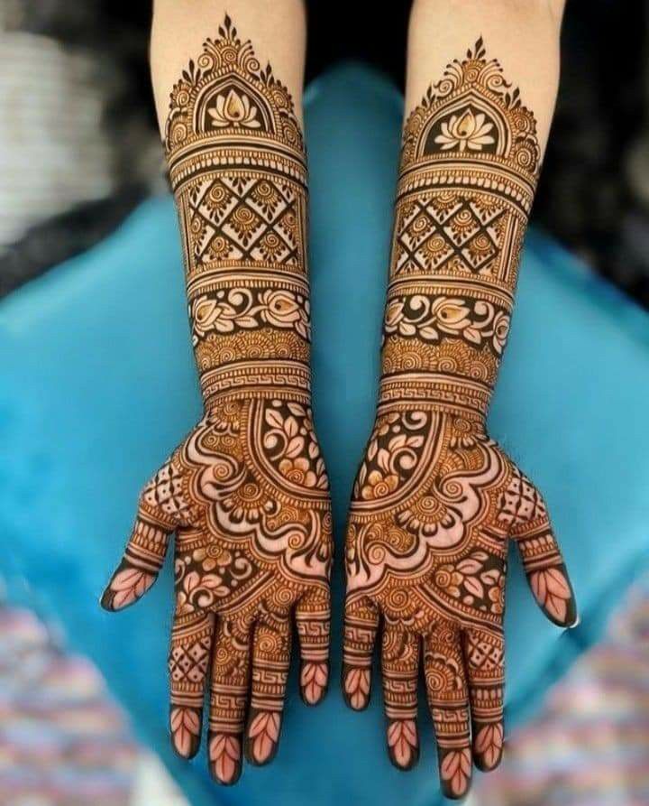 two hands with henna tattoos on them, one is showing the intricate pattern and the other has an elaborate design