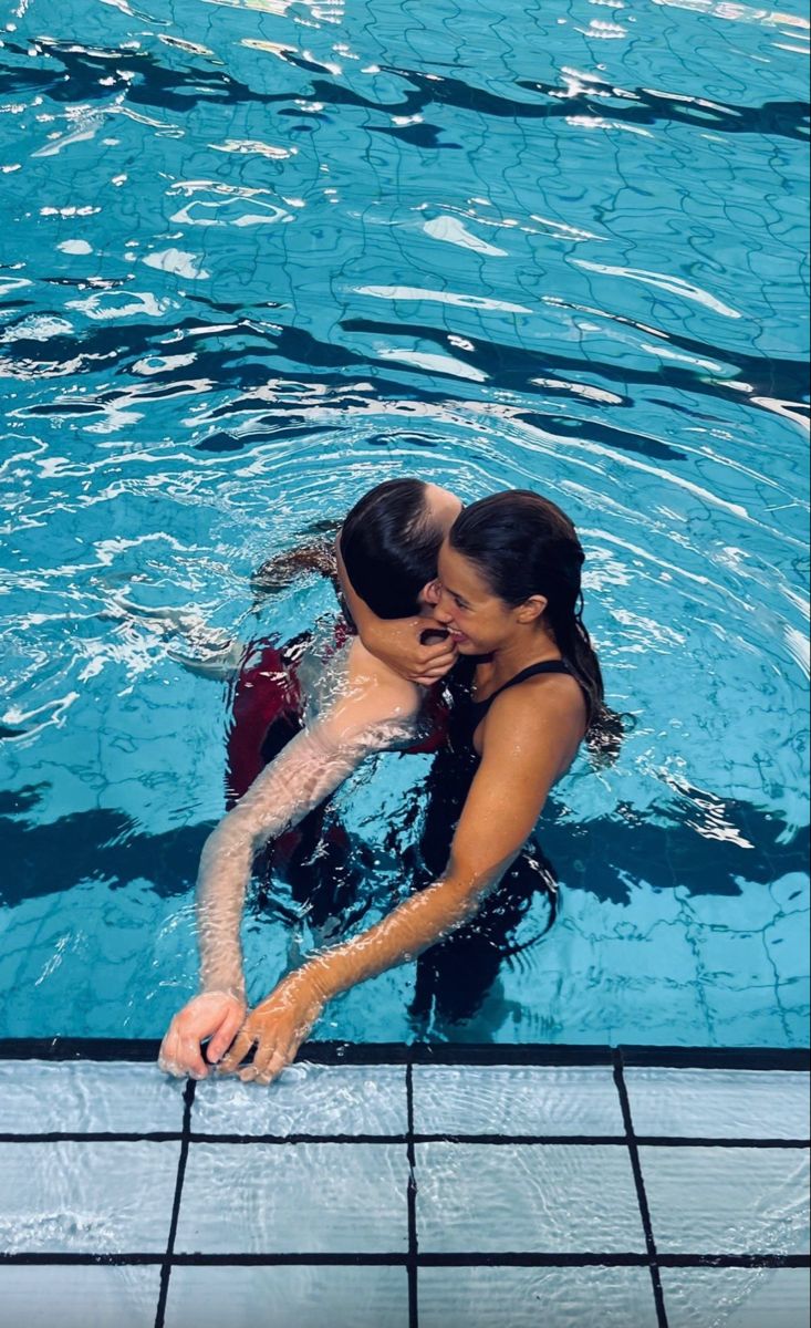 a man and woman are kissing in the swimming pool with their arms around each other