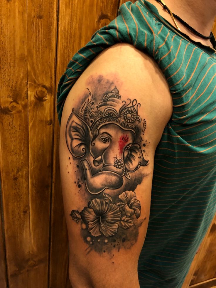 a man with a tattoo on his arm that has an elephant and flowers around it