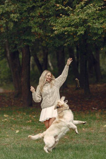 a woman is playing with her dog in the park