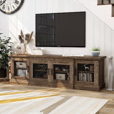 a large flat screen tv sitting on top of a wooden entertainment center in a living room