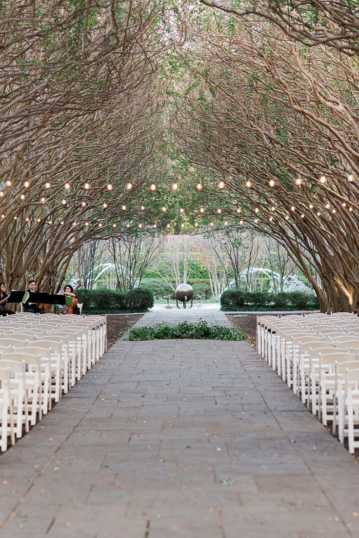 an outdoor ceremony setup with white chairs and lights