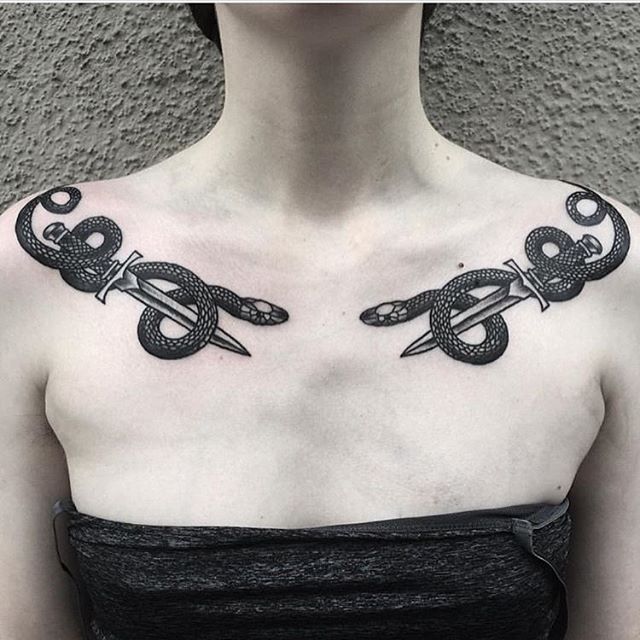 a woman with tattoos on her chest and scissors in the shape of two serpents