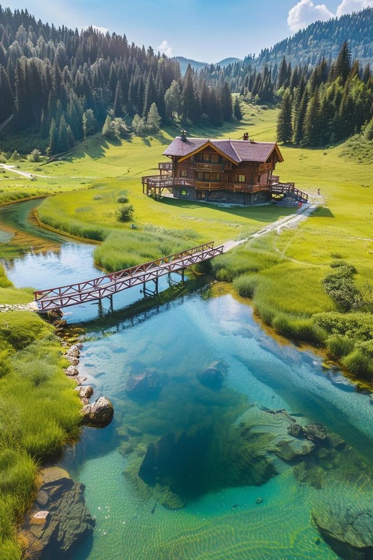 an aerial view of a house on the side of a river with a bridge over it