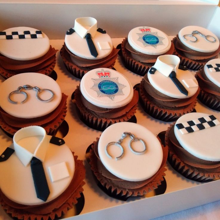 cupcakes decorated with ties and handcuffs are in a box