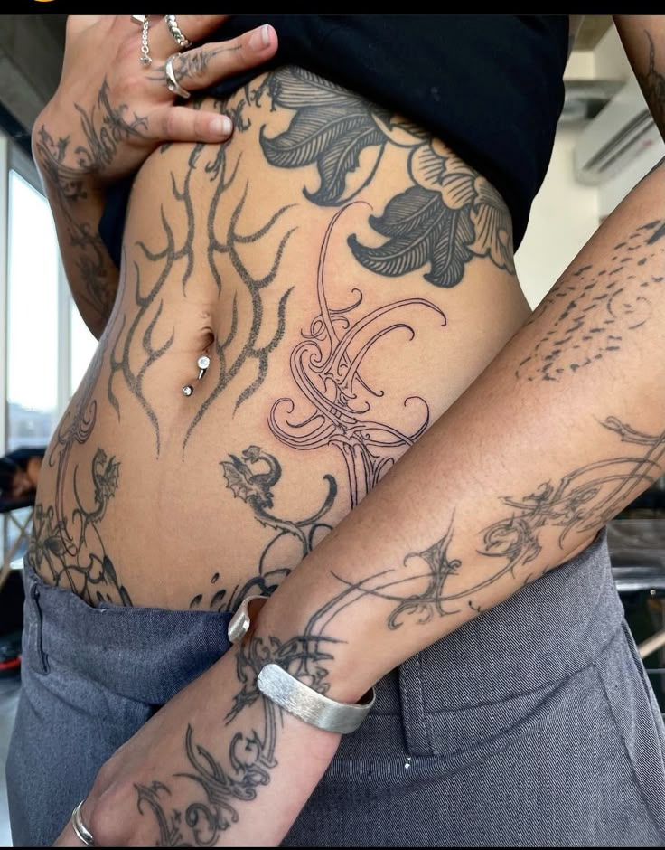 a woman with tattoos on her stomach is holding onto another person's arm and belly