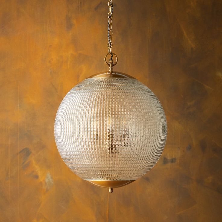 a white ball hanging from a chain on a brown wall with a cross in the center