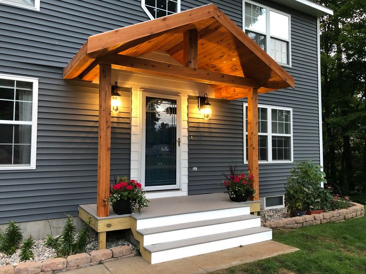 a house with a covered porch and steps leading up to the front door that is lit by lights