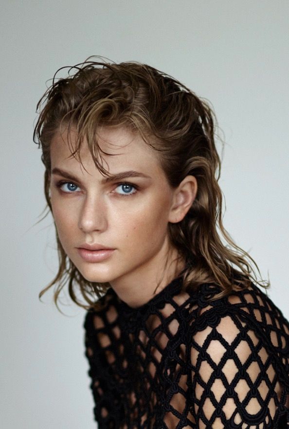 a woman with blue eyes is posing for a magazine cover shoot, and has her hair pulled back into a messy ponytail