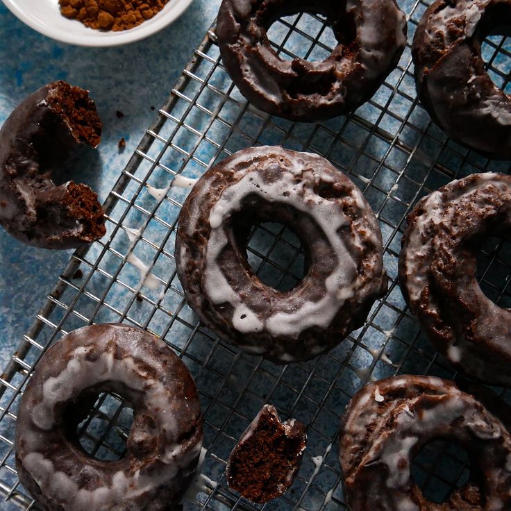 chocolate donuts with white glaze on cooling rack next to bowl of powdered sugar