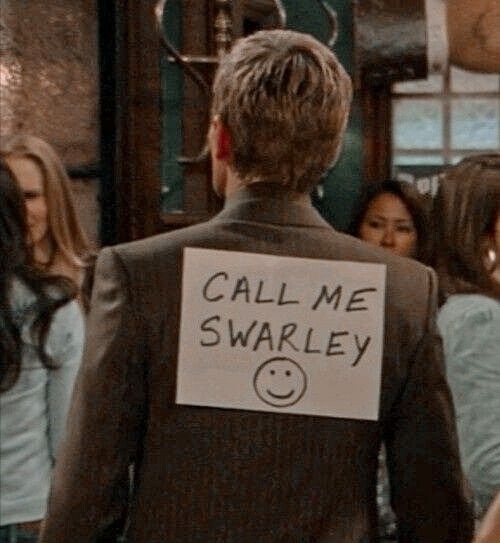 a man with a sign on his back that says call me swarley in front of other people