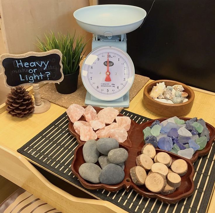 a table topped with lots of different types of rocks next to a scale and potted plant