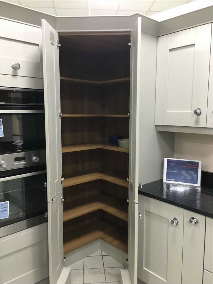 a kitchen with white cupboards and black counter tops is shown in this image, there is an open door to the pantry