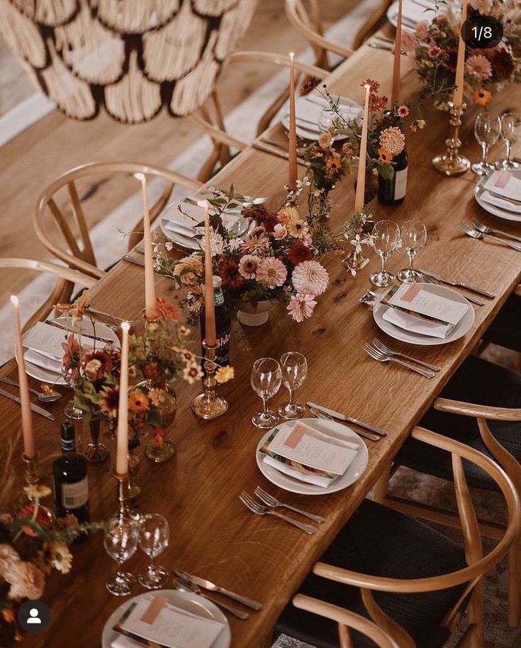 the table is set with candles, plates and glasses for dinner guests to eat at