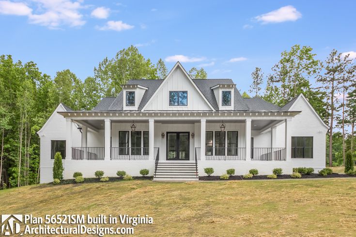 a white two story house in the middle of a wooded area with stairs leading up to it's front door