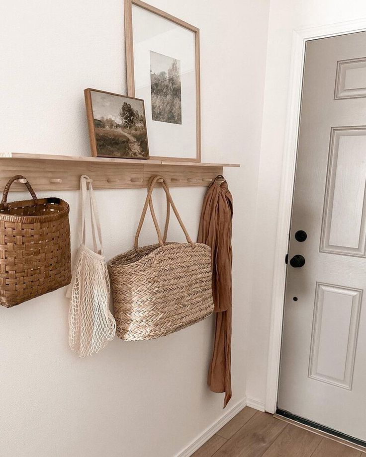 two purses hanging on the wall next to a basket and coat rack with hooks