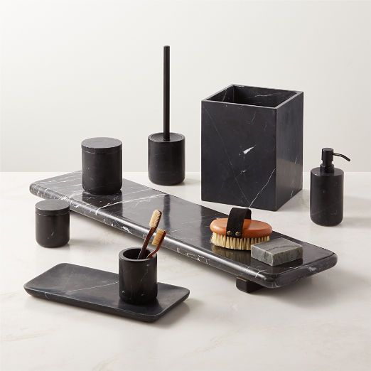 an assortment of black bathroom accessories including soap, brush and toothbrush on a marble countertop