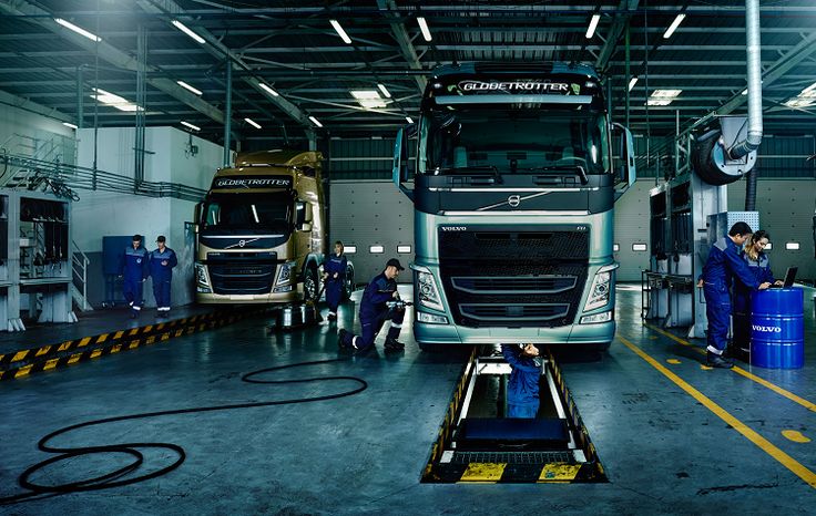 two large trucks in a warehouse with workers around them