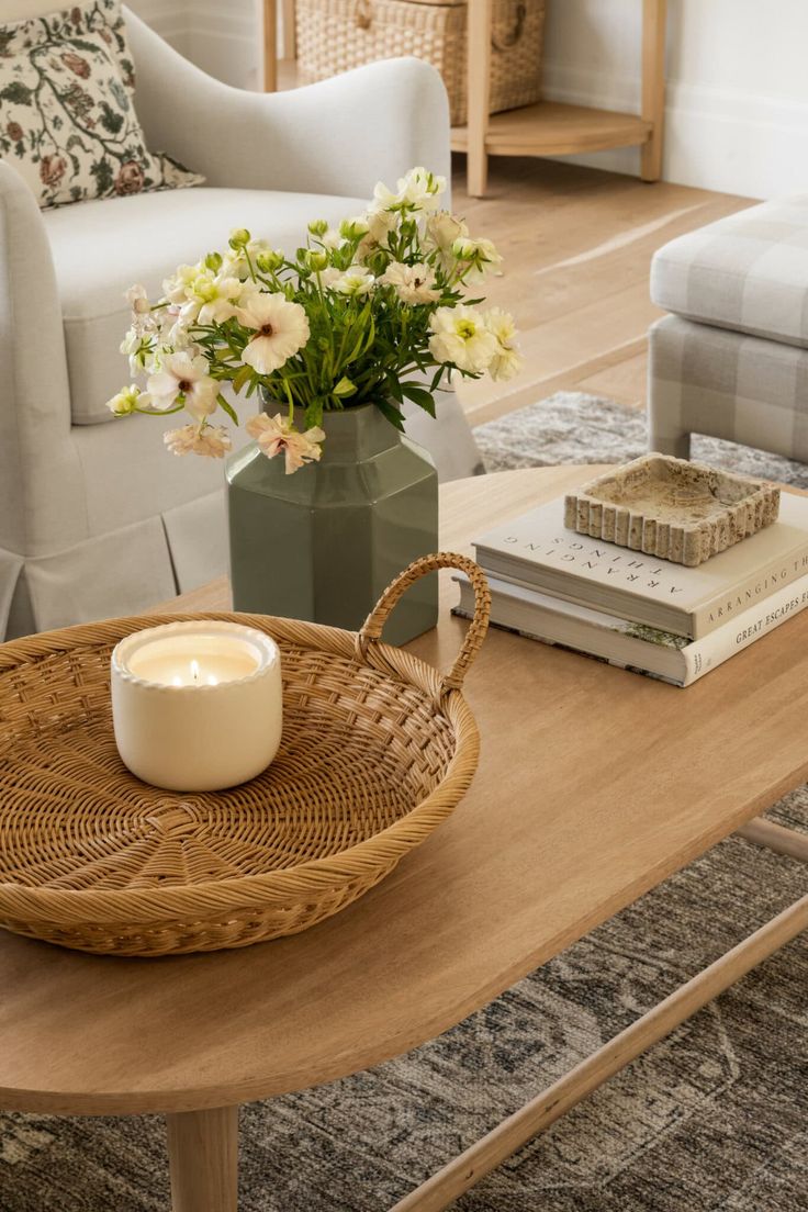 a wicker basket on a coffee table with a candle and flowers in the center