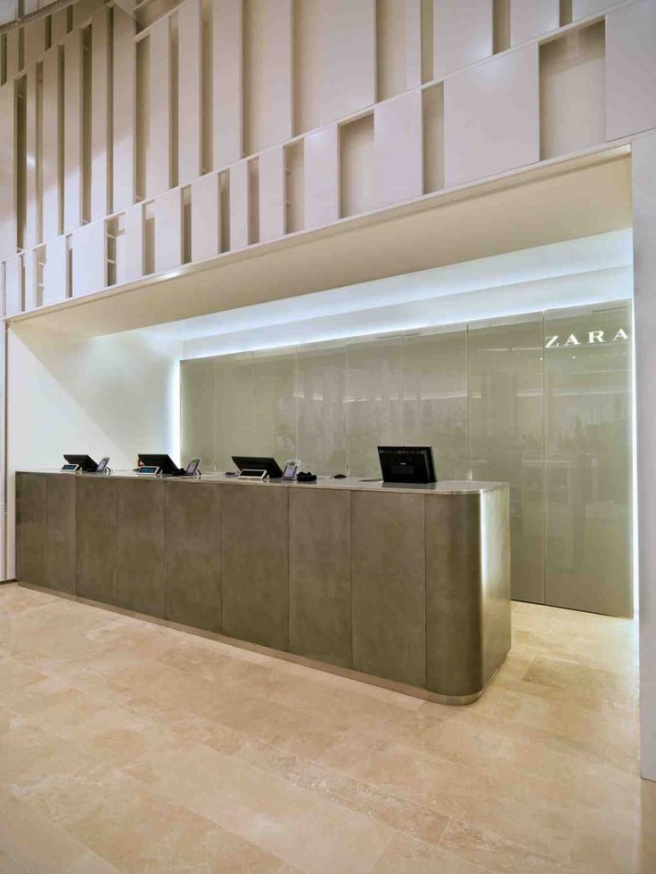 an empty reception area with laptops on the counter in front of it and stairs leading up to the second floor