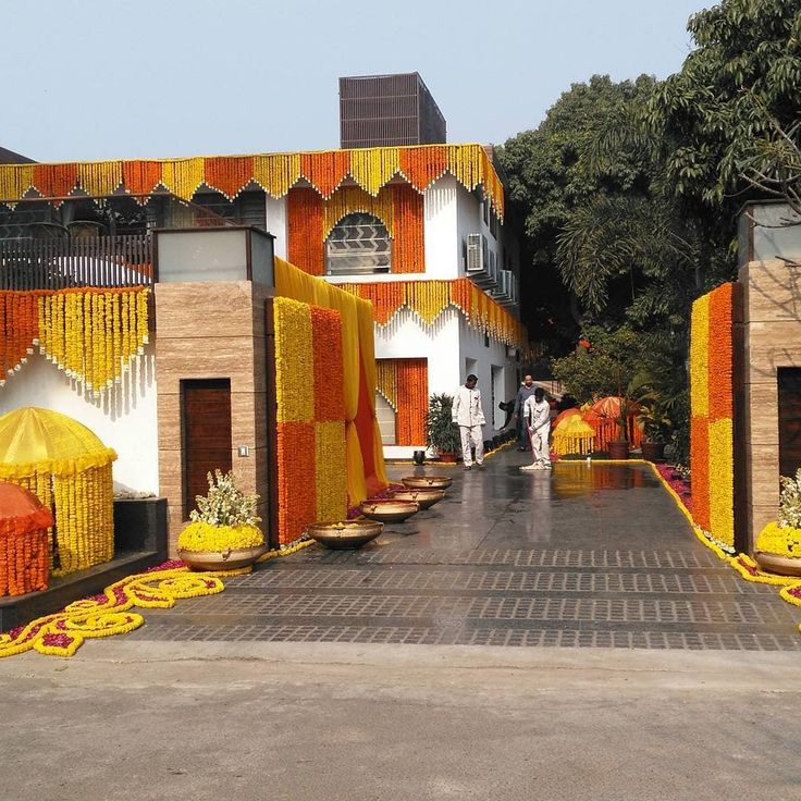 an outdoor wedding venue with yellow and orange decorations on the side walk, surrounded by trees