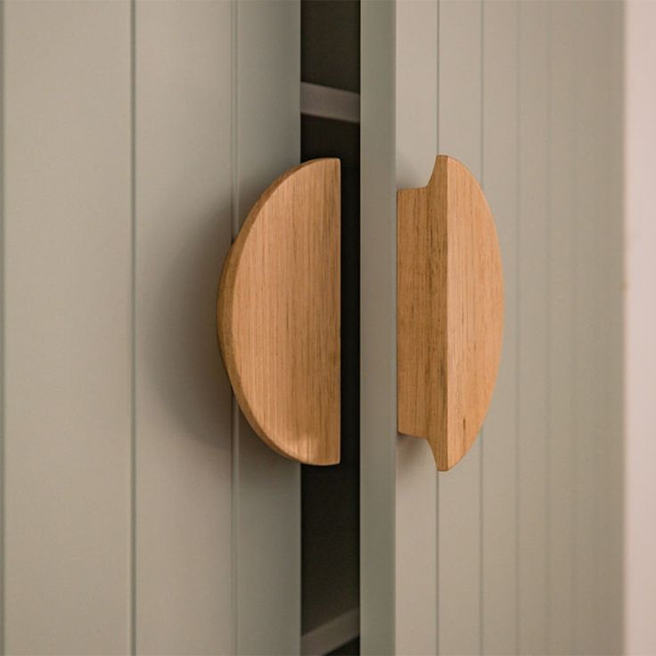 a close up of a wooden door handle on a white cabinet with grey paint and wood trim