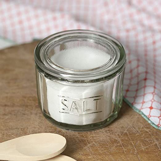 a spoon sitting next to a jar with salt in it