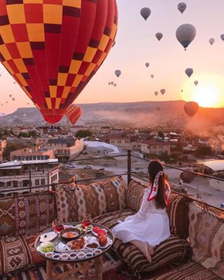 a woman sitting on top of a couch next to a hot air balloon filled with balloons