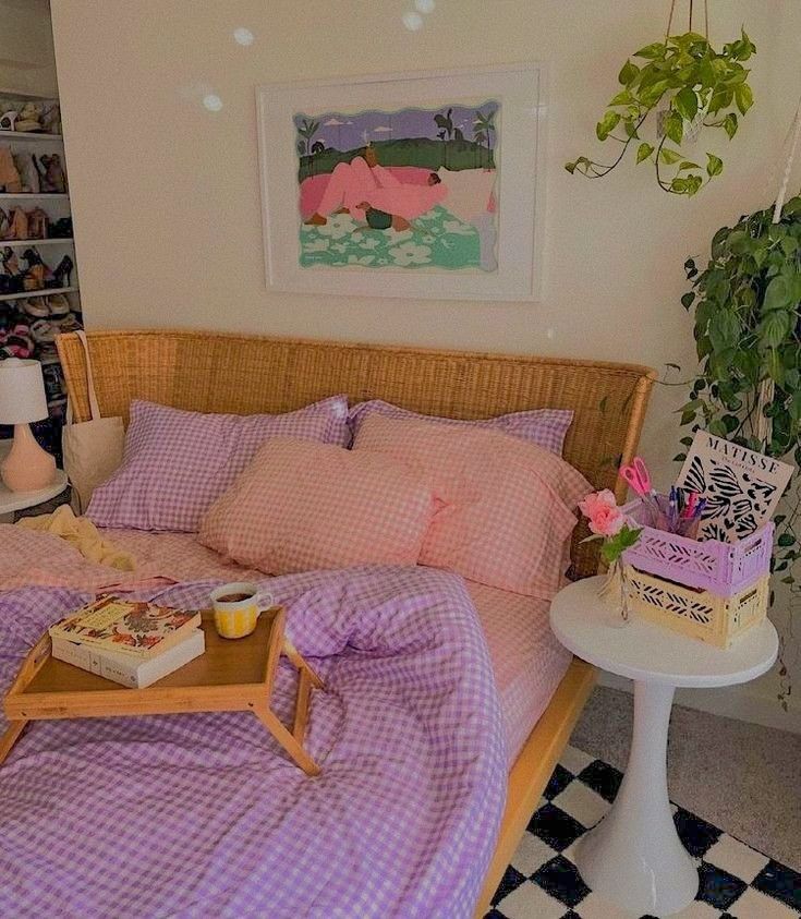 a bed sitting next to a table with books on it and a potted plant