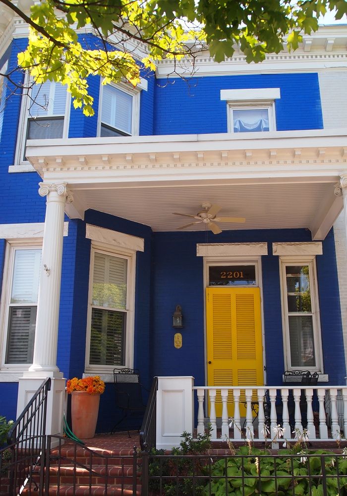 a blue house with yellow door and white trim on the front porch is seen in this image