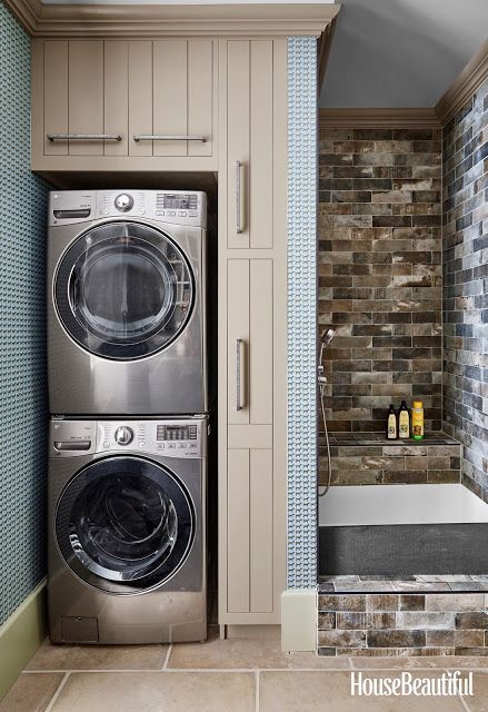 a washer and dryer in a bathroom with blue tiles on the wall behind them