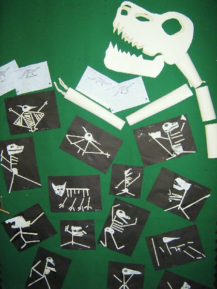 some paper cutouts and stickers on a green surface with a skeleton in the middle