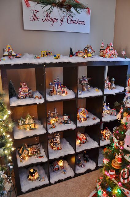 a christmas display in the corner of a room with many ornaments on shelves and trees